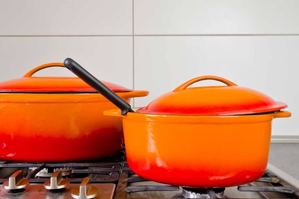 two orange red pots standing on the stove