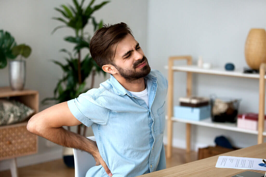 man sitting on a chair at a table with back pain