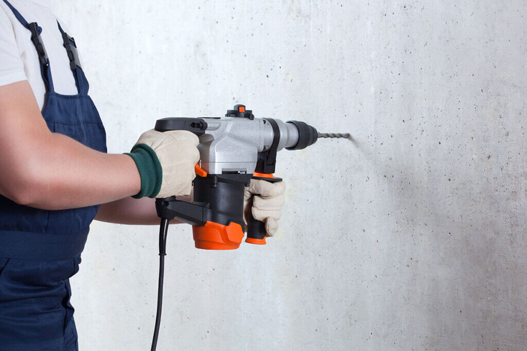 man standing in front of a wall with an impact drill