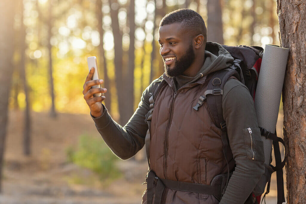  man in the forest looks happily at his smartphone