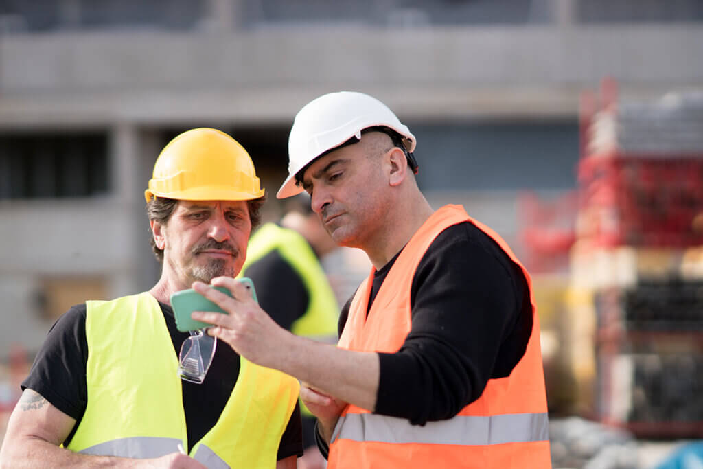  construction workers use smartphone on a building site