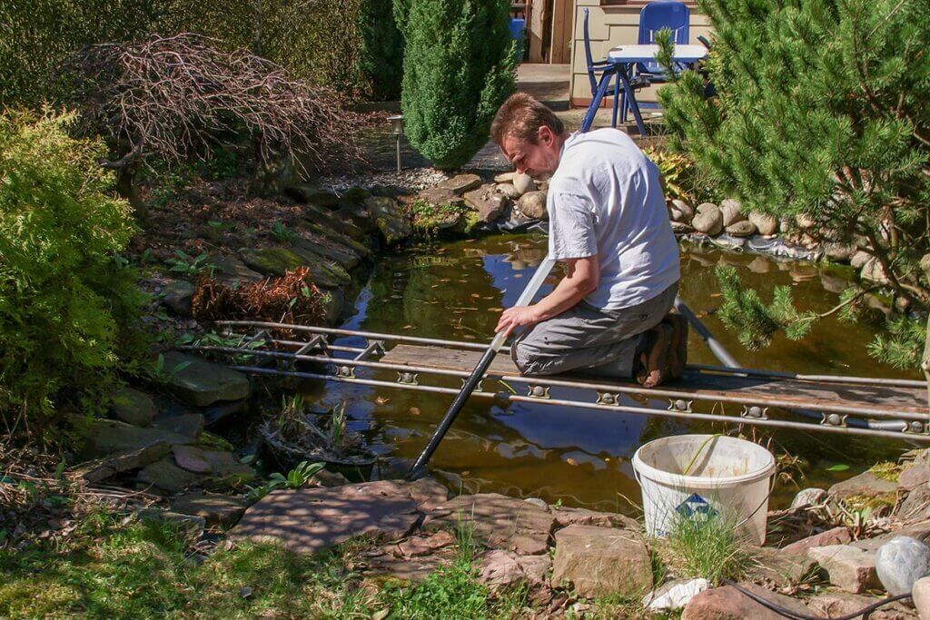 man uses sludge suction on home pond