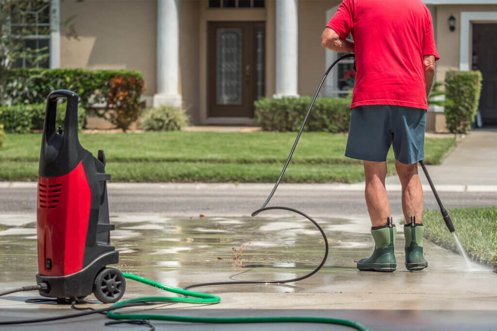 man cleans the driveaway with a pressure washer