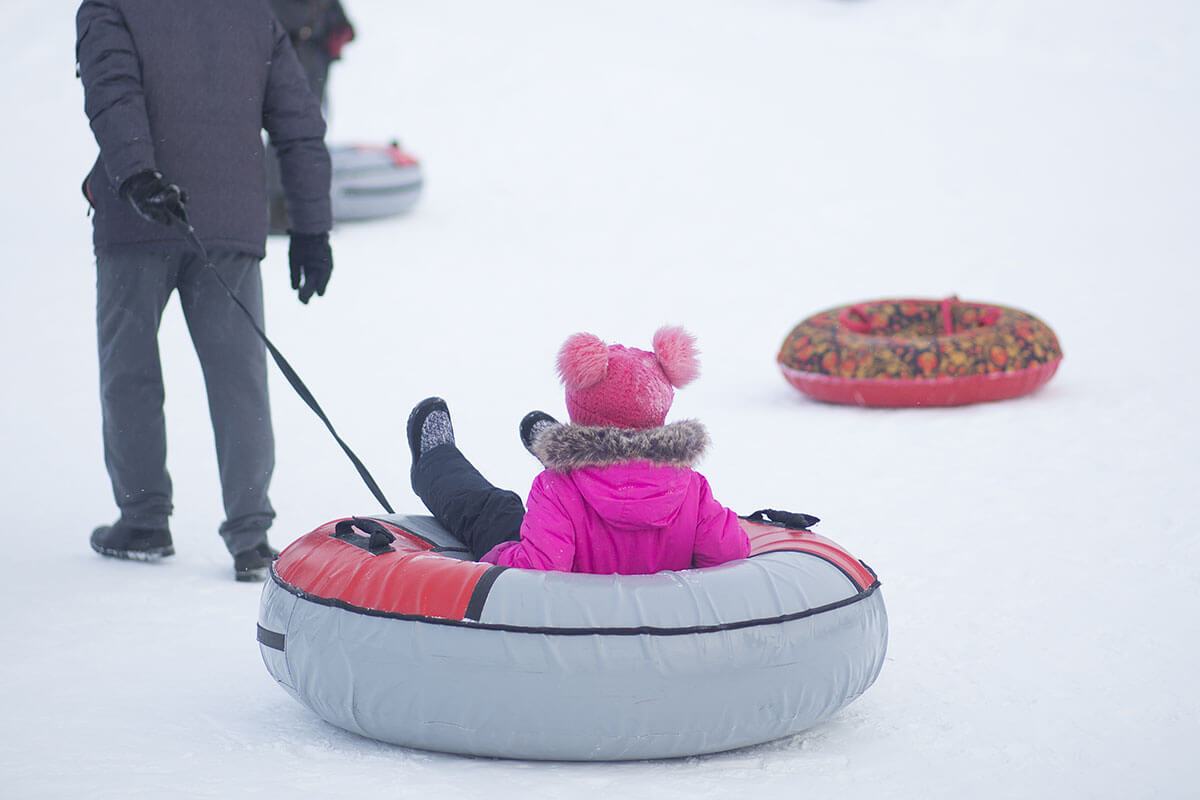 Child being pulled along on an inflatable sled.